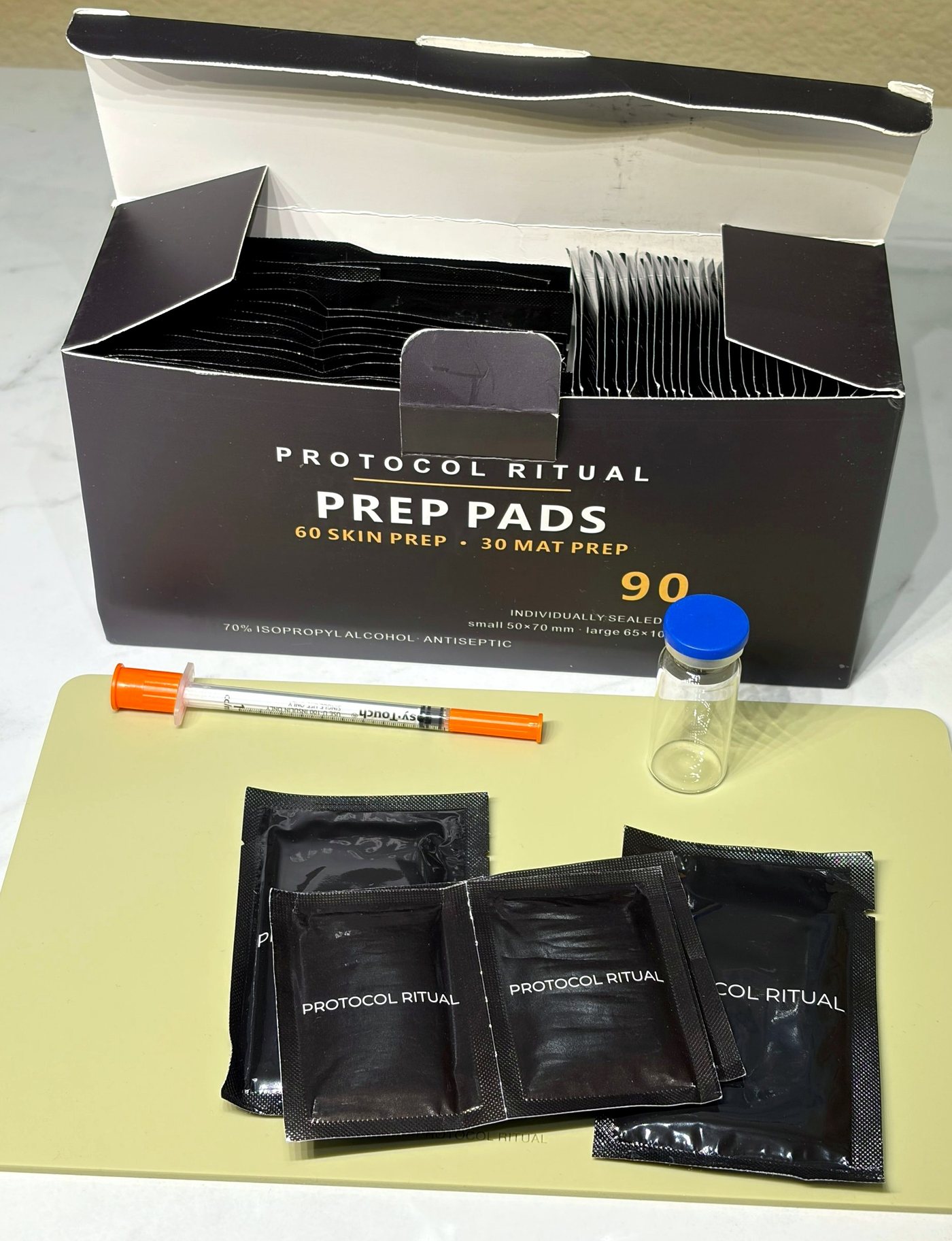 An open box of 90 Protocol Ritual prep pads with pads laid on a sage mat