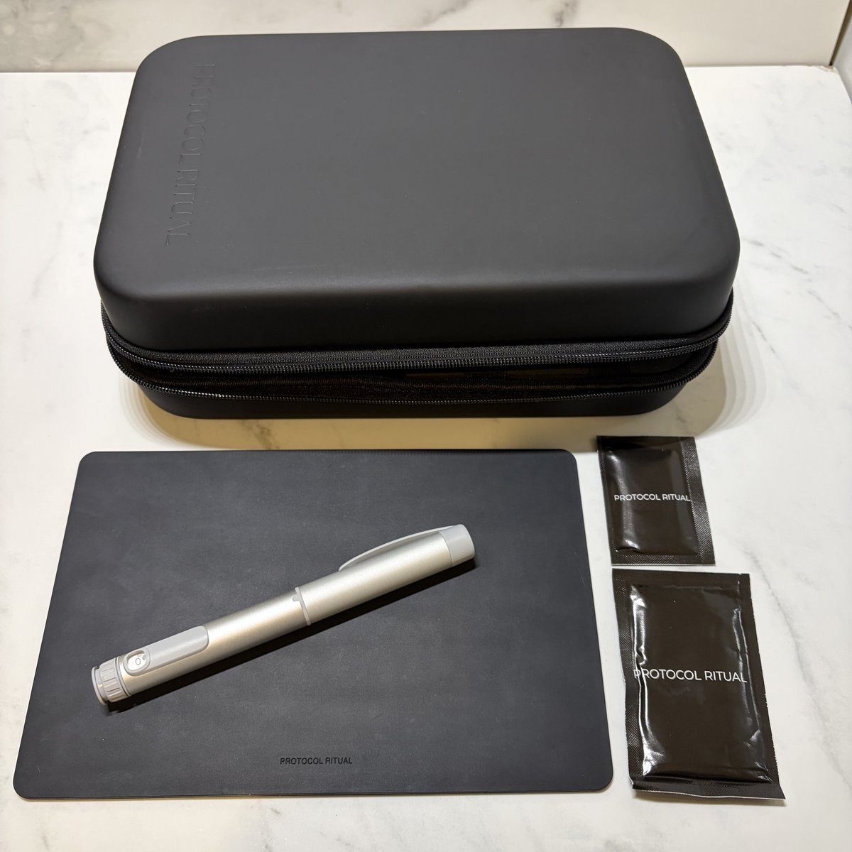 Closed matte black Protocol Ritual case with a GLP-1 pen on the silicone prep mat